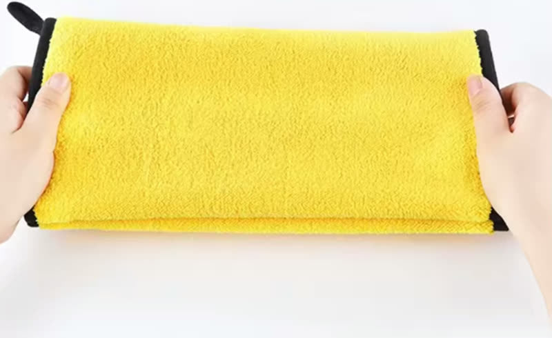 Hands holding a soft yellow microfiber pet towel